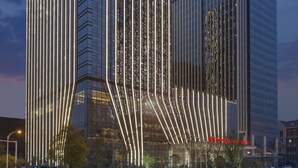 Un hôtel moderne au design vertical original et à la façade en verre réfléchissant.