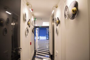 A hallway with a striped floor, multiple wall-mounted fans, and a door at the end. - The 22 Hotel (Istanbul)