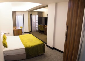 Une chambre d’hôtel comprenant un lit, un bureau, une chaise, une télévision et une armoire.