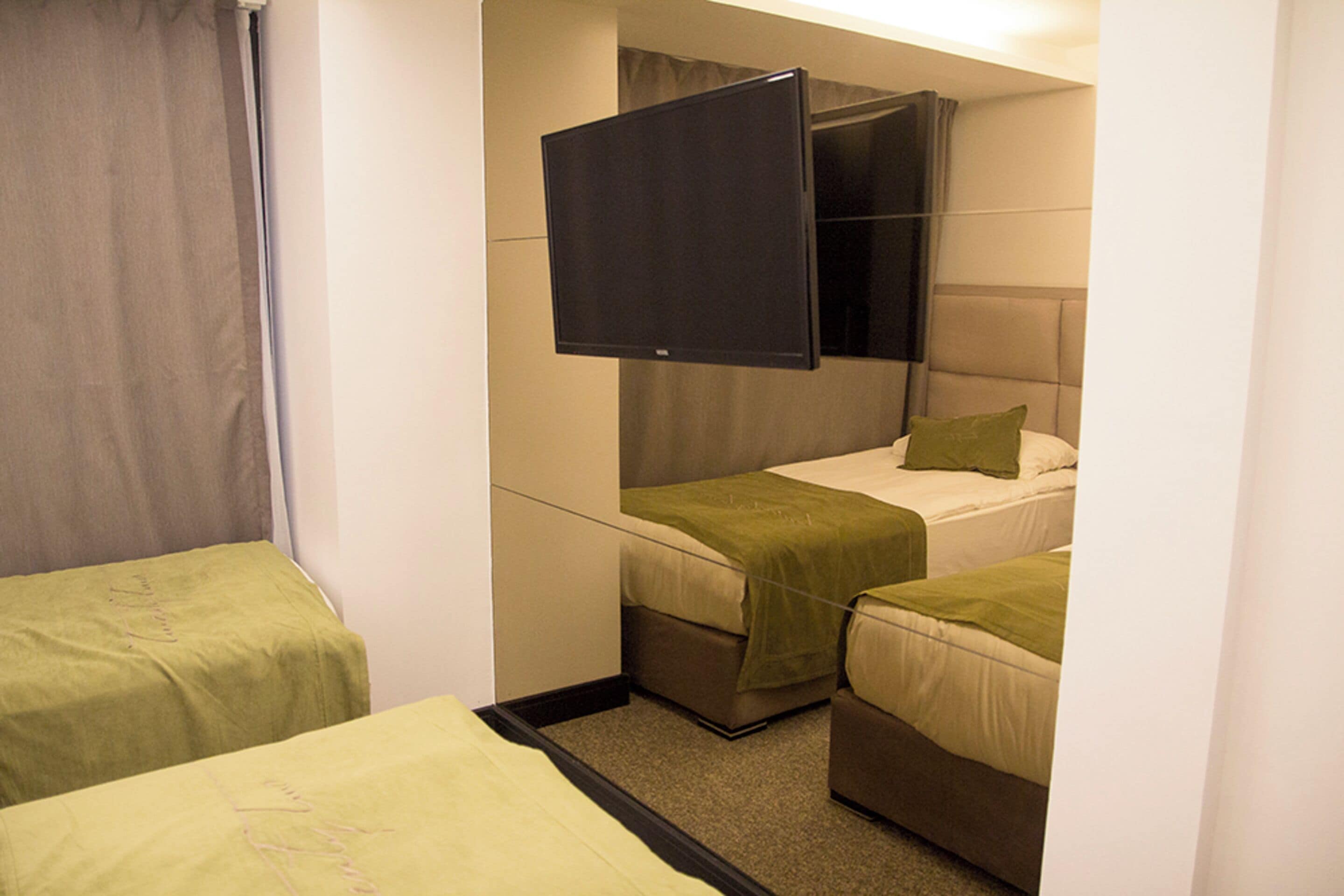 Habitación de hotel con dos camas individuales, un televisor de pantalla plana y una pequeña zona de estar.