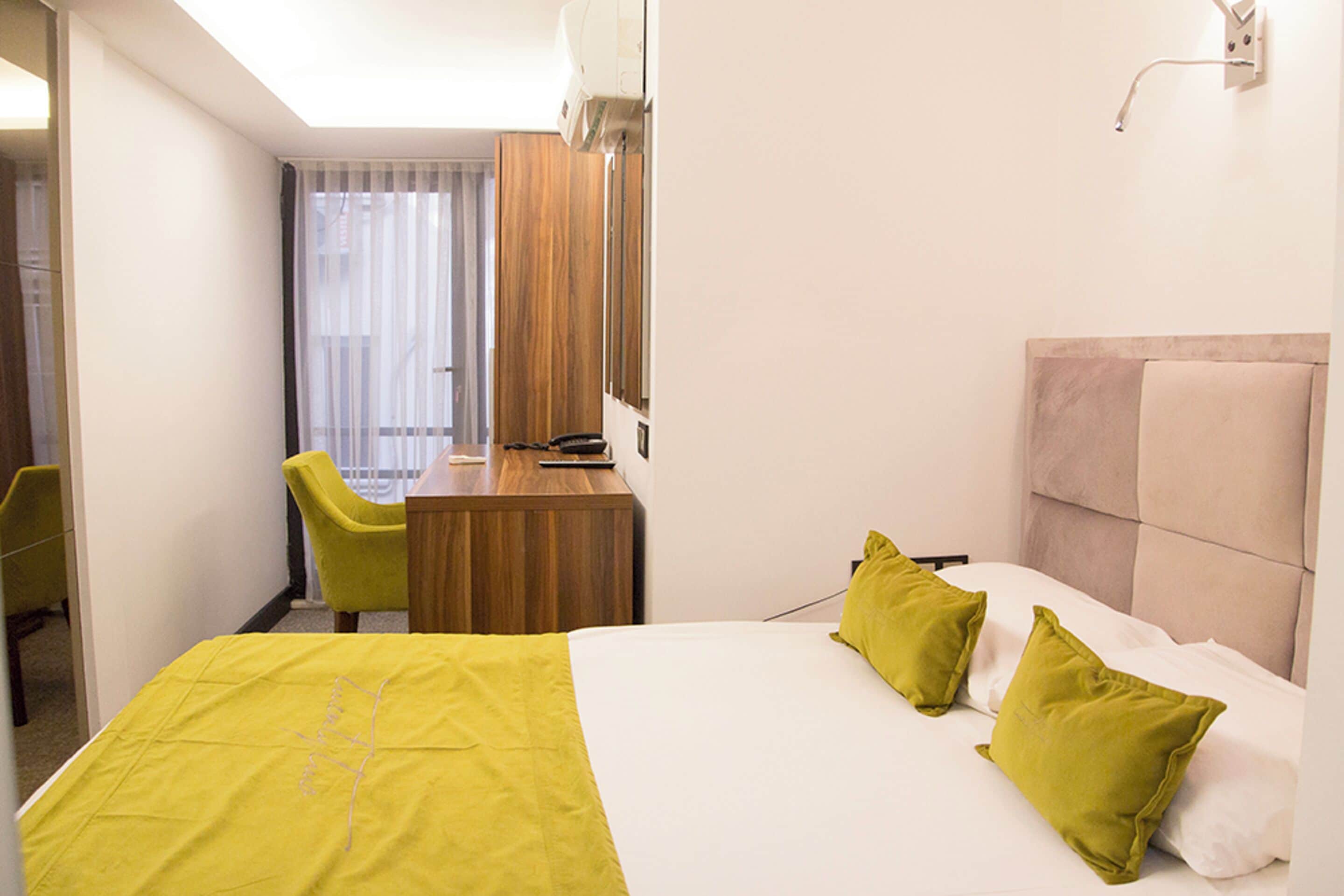 Une chambre d’hôtel avec un lit, un bureau, une chaise et une fenêtre avec des rideaux.