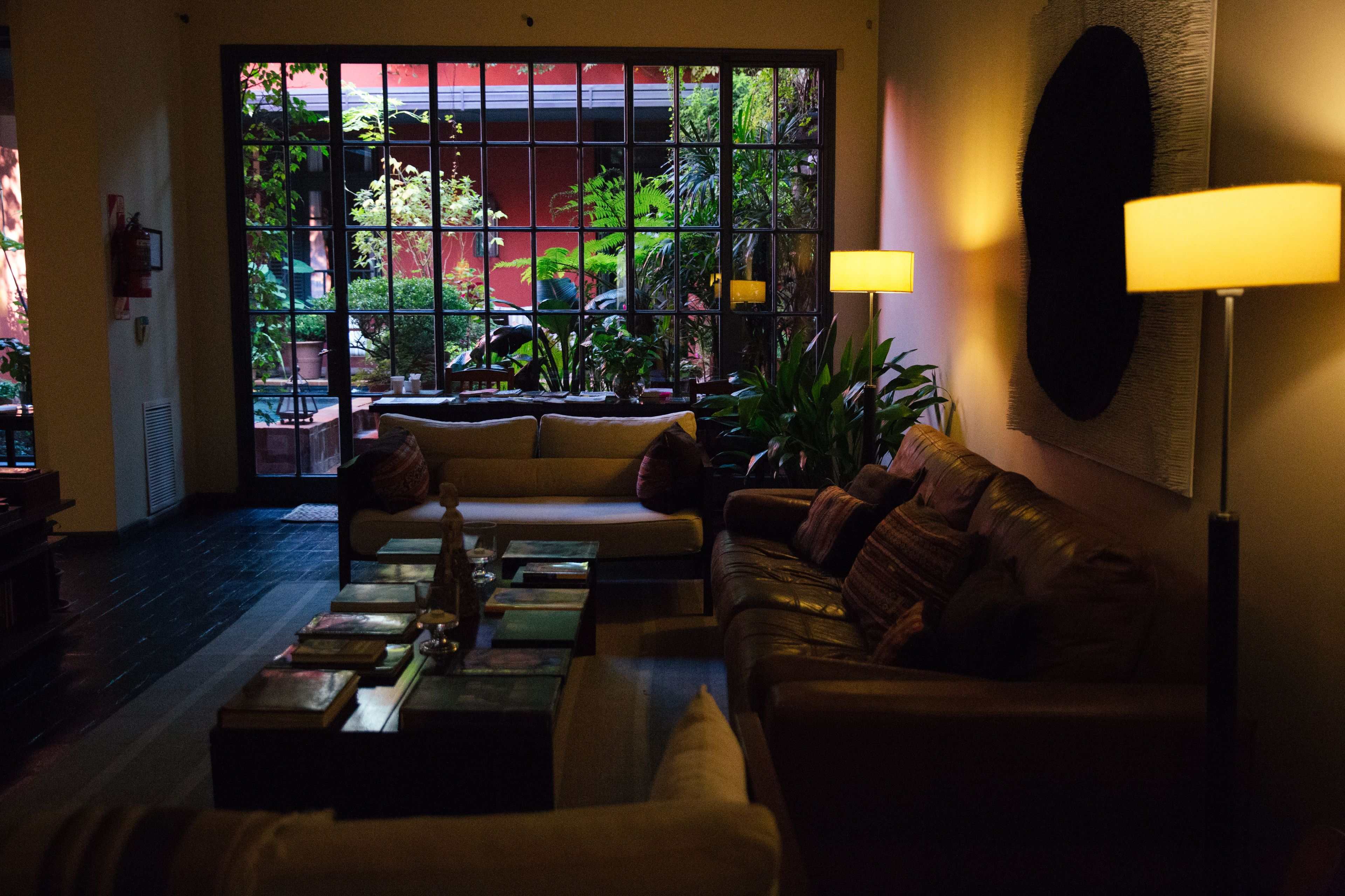 Un salón acogedor con sofá, una mesita de centro y vistas a un jardín a través de un ventanal grande.