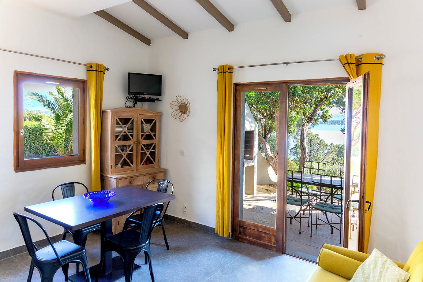 A dining area with a table, chairs, a cabinet, and a TV.