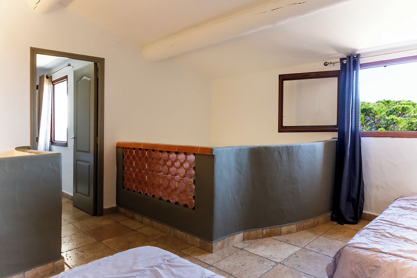 Une chambre d’hôtel avec un lit, un petit bureau, un miroir et une vue sur la verdure.
