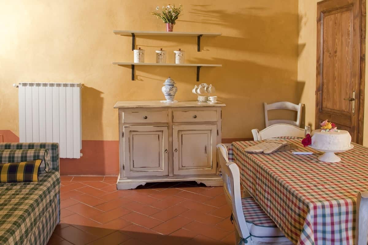 Een eethoek met een tafel gedekt voor twee personen, een plafondventilator, een radiator en een houten deur.