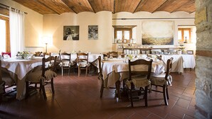Un espace repas comprenant plusieurs tables et chaises, des poutres en bois au plafond et des œuvres d’art accrochées aux murs.
