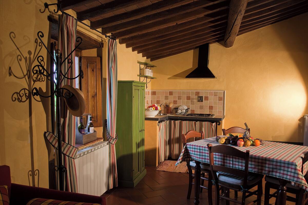 Een gezellige keuken met een eethoek, met een houten plafond, een groen kastje en een tafel gedekt met een geruit tafelkleed.
