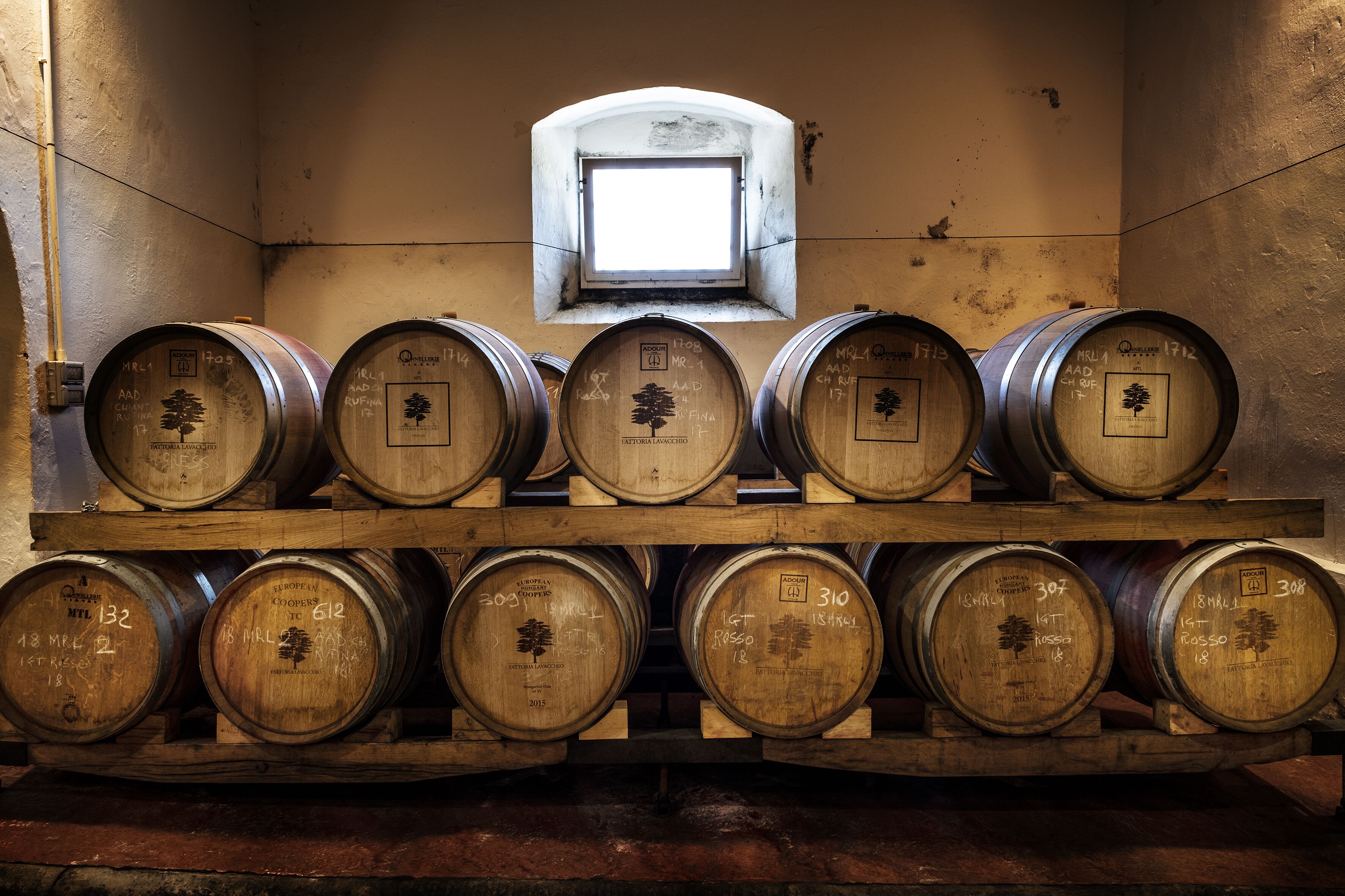 Wooden barrels arranged in two rows on shelves, with a small window above.