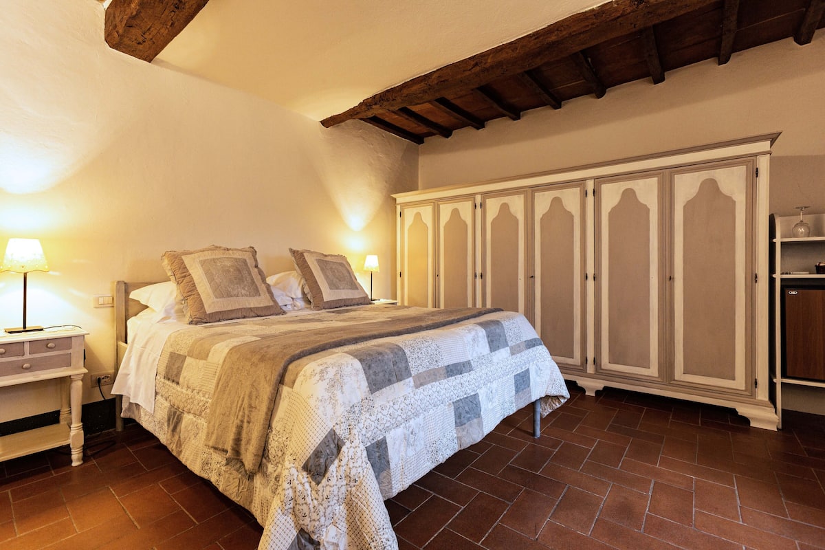 Een slaapkamer met een bed, nachtkastjes, een kledingkast en een betegelde vloer.