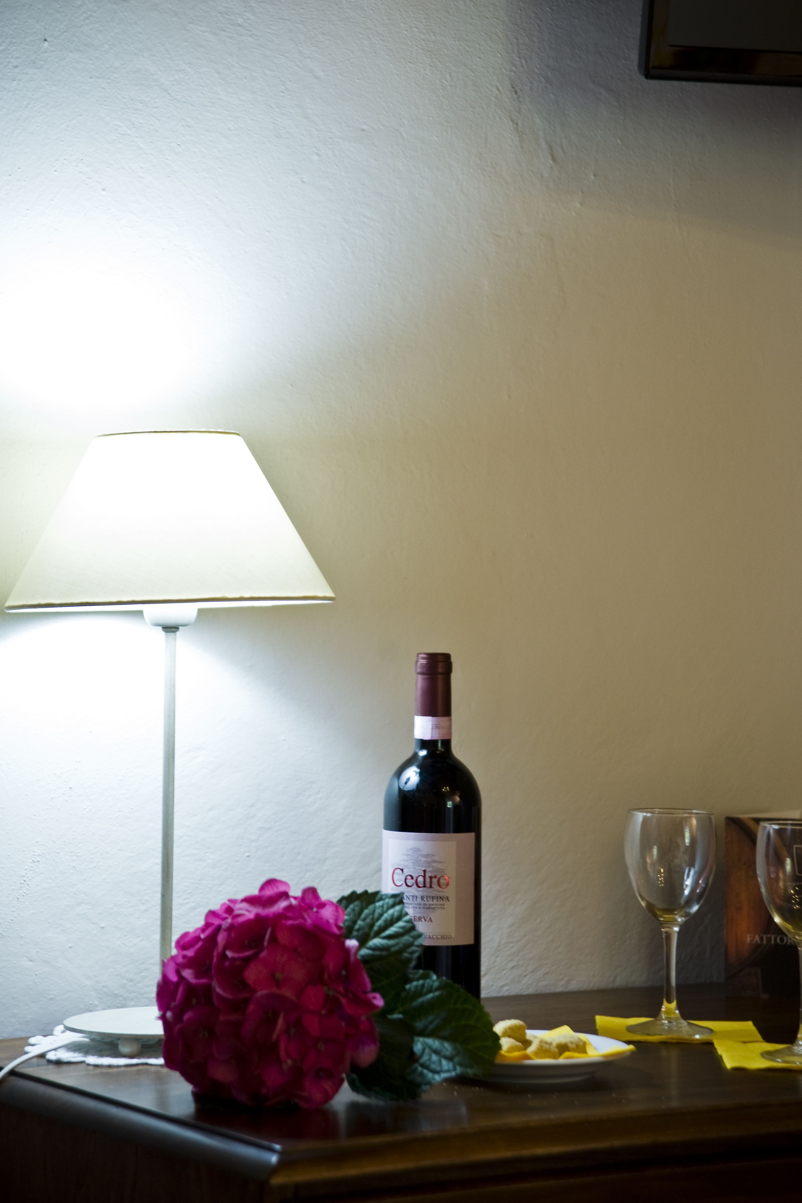 Una mesa con una botella de vino, una copa y una flor.