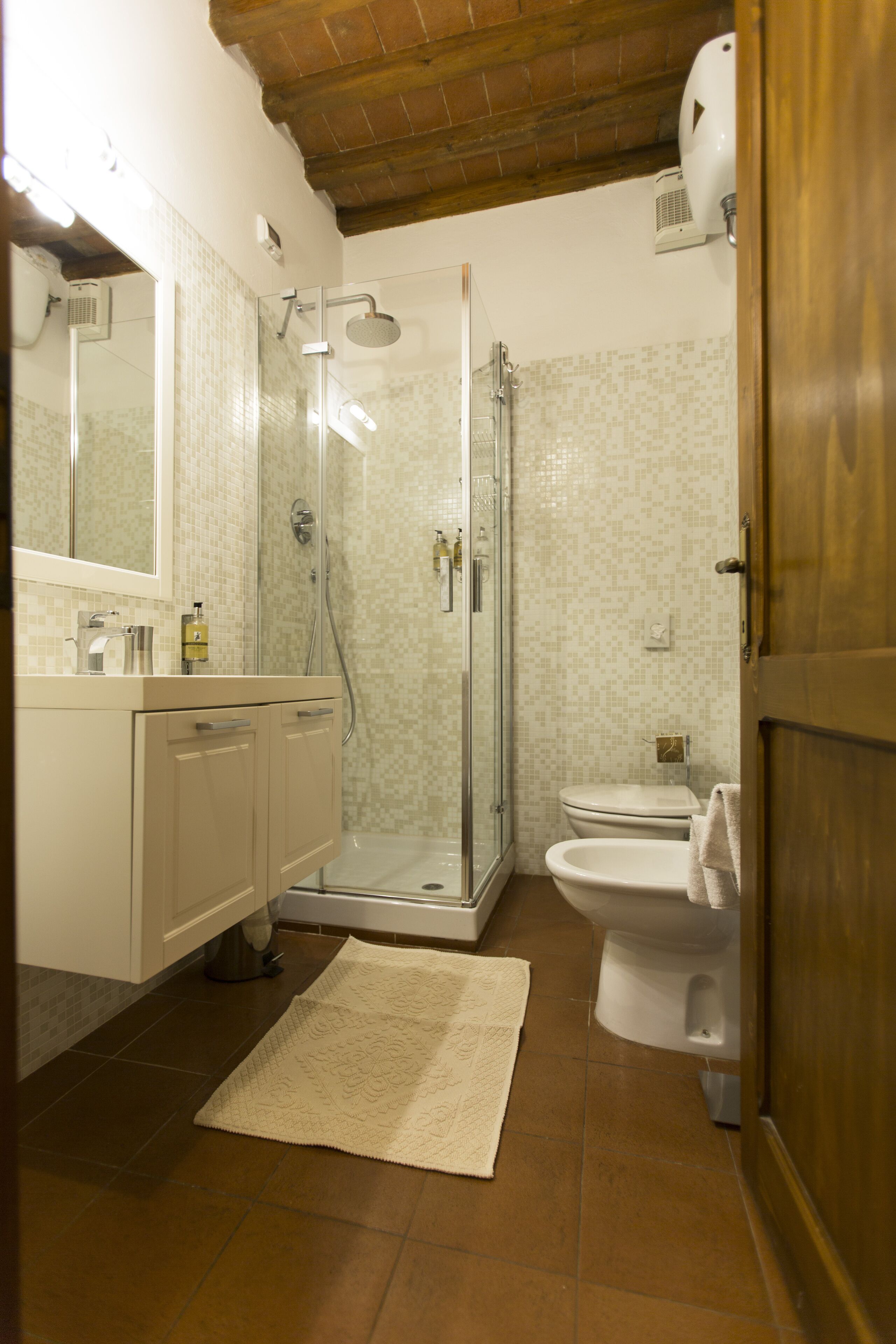A bathroom with a glass-enclosed shower, a toilet, and a sink with a mirror.