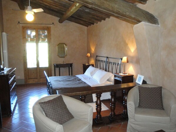 Une chambre à coucher comprenant un lit, deux tables de chevet, une commode, une chaise, un bureau, un miroir et un ventilateur de plafond.