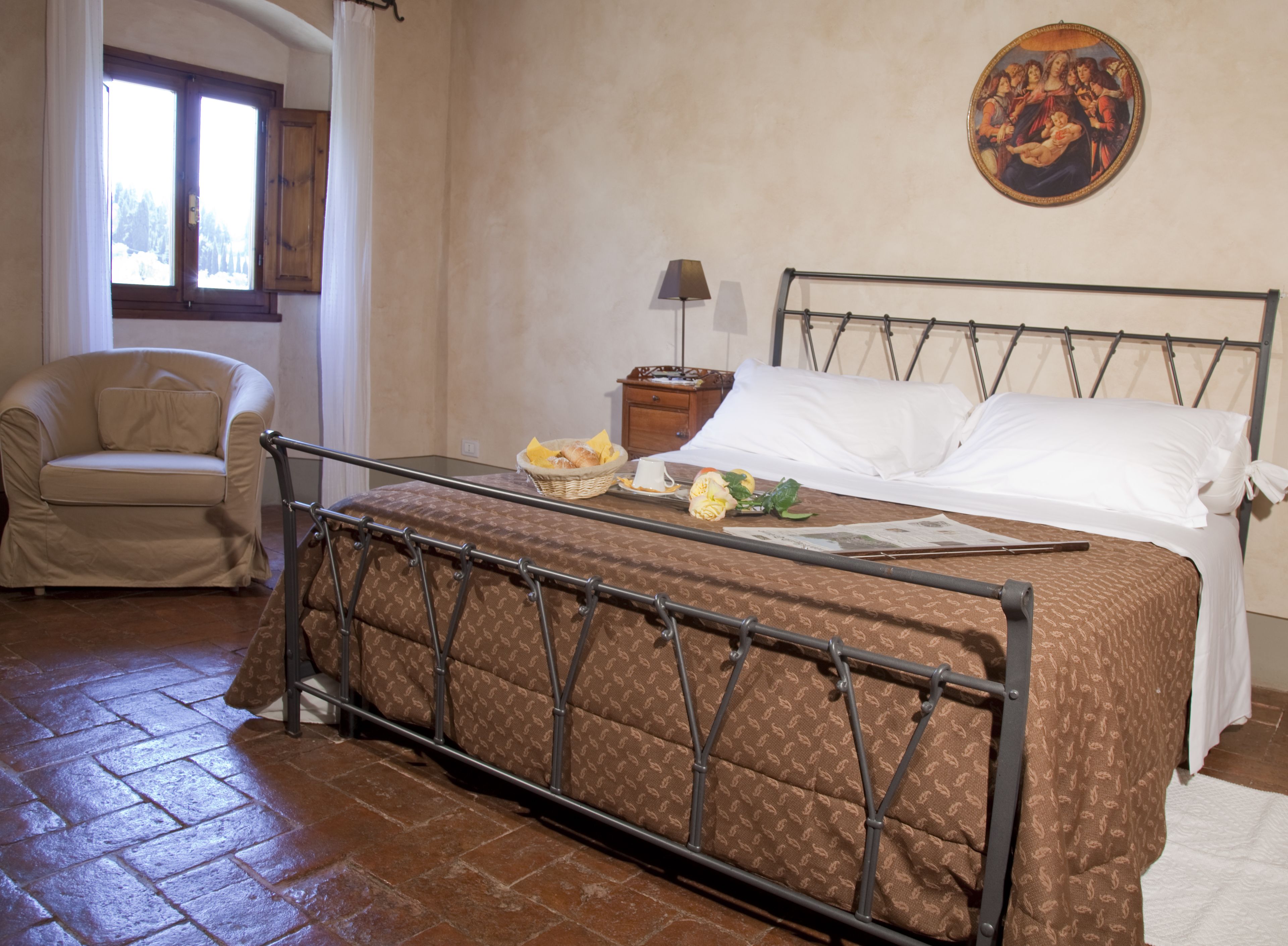 A bedroom with a bed, a chair, a nightstand, and a painting on the wall.
