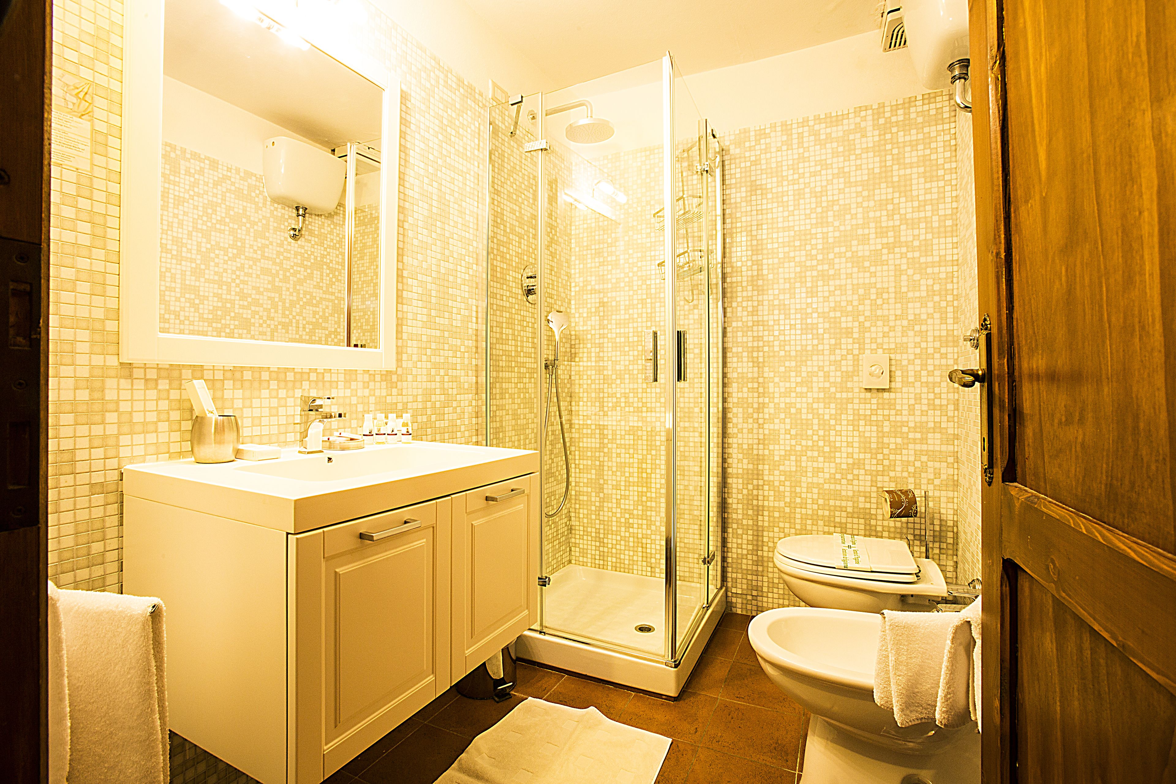 Ein Badezimmer mit Duschkabine, Waschbecken mit Spiegel und Toilette.