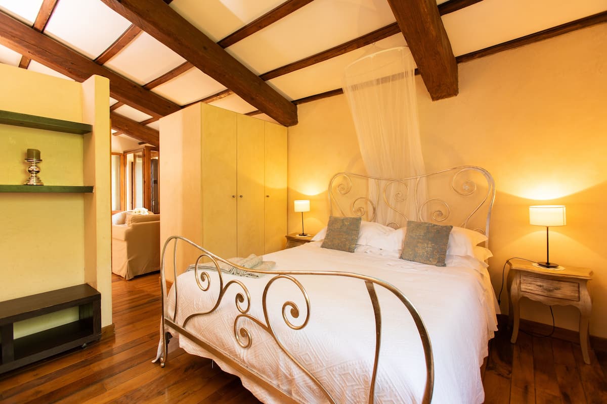 Een slaapkamer met een bed, nachtkastjes, een lamp, een kledingkast en een plafondventilator.