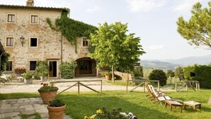 Un bâtiment en pierre recouvert de lierre, avec des places assises à l’extérieur et une vue sur la campagne.