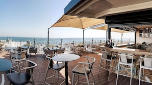 An outdoor terrace with tables and chairs, a bar area, and a view of the sea. - Aprilis Hotel - Special class (Istanbul)