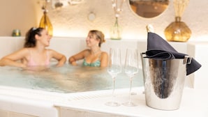 Zona de spa con un jacuzzi, dos copas de vino vacías y un cubo con un paño.