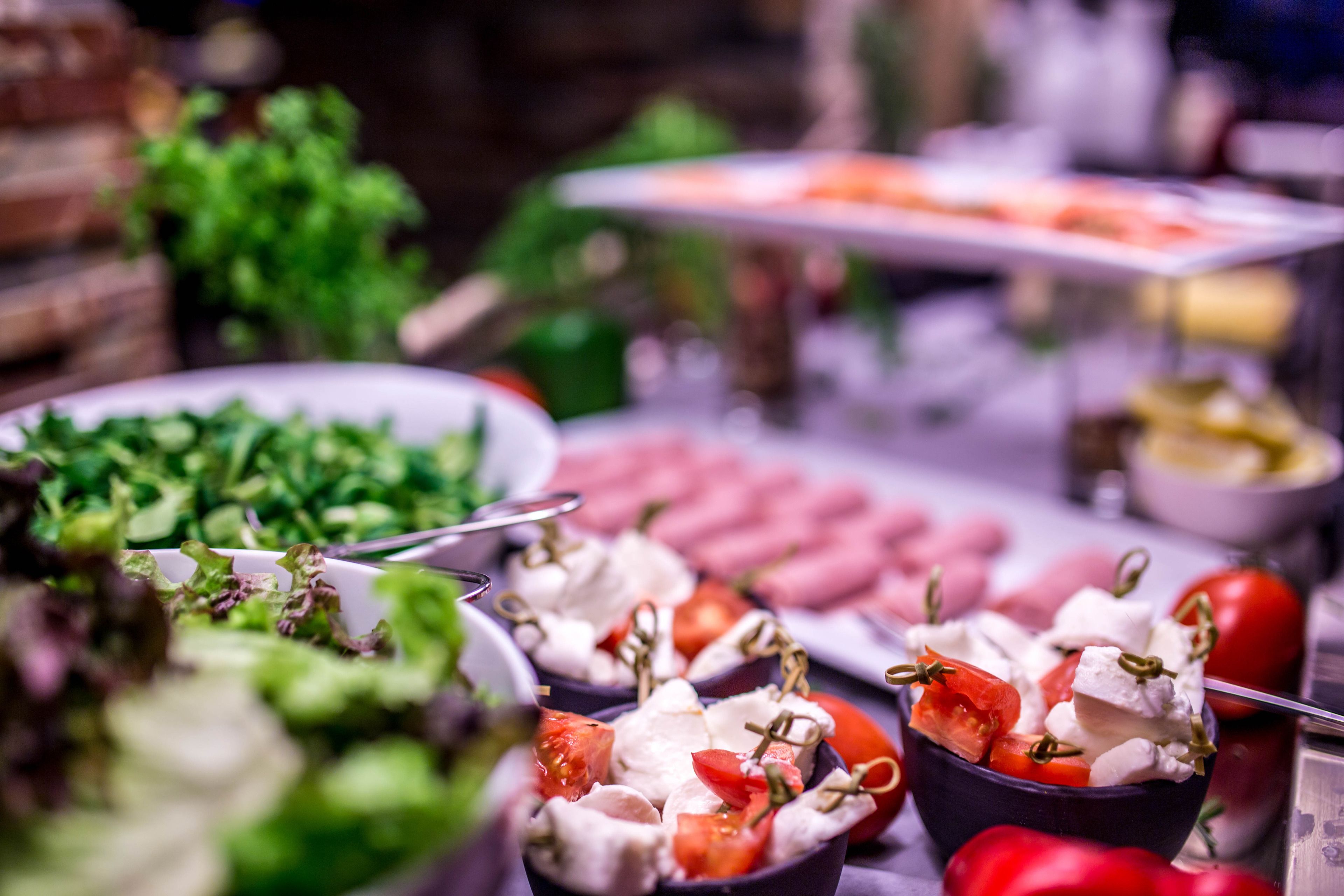 A buffet with various food items including salads, cheeses, and meats.