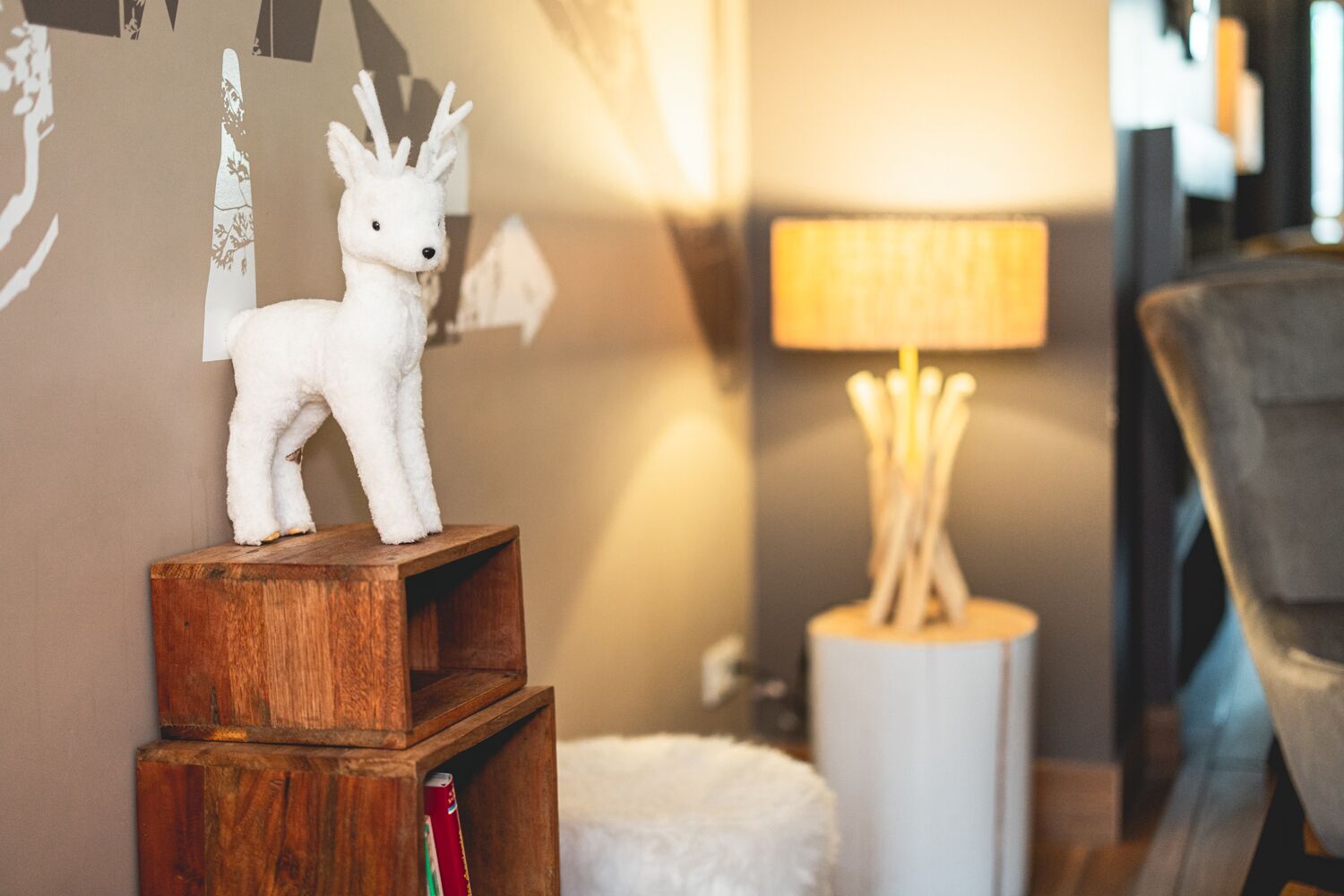 En blød bamse på en træhylde, en lampe og en hvid, lodden genstand.