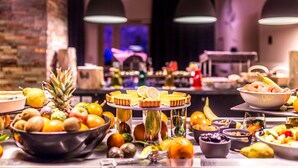 Una mesa de buffet con varias frutas, una piña y una presentación de postres.