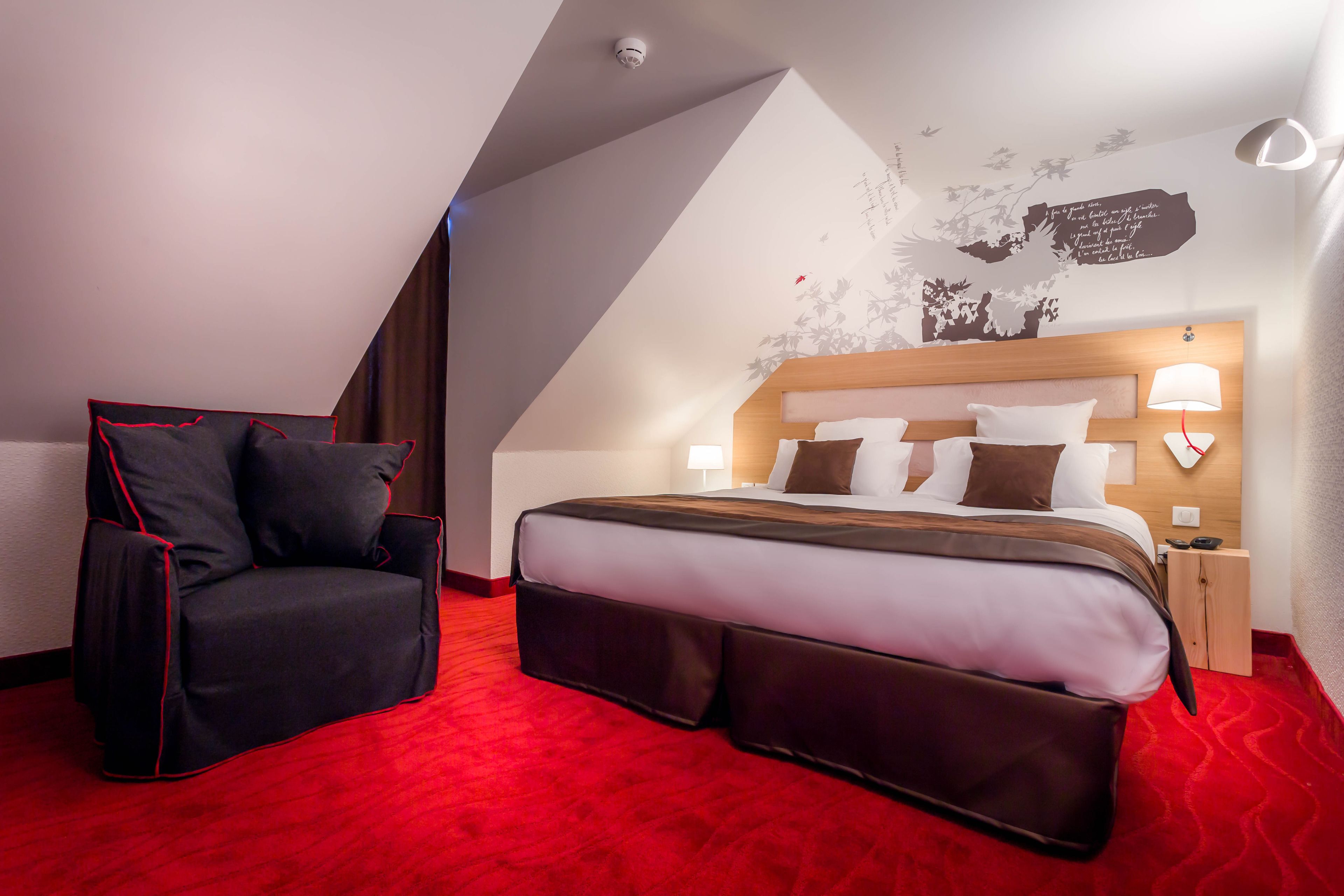 A hotel room with a bed, a chair, a nightstand, and a wall with a map and text.