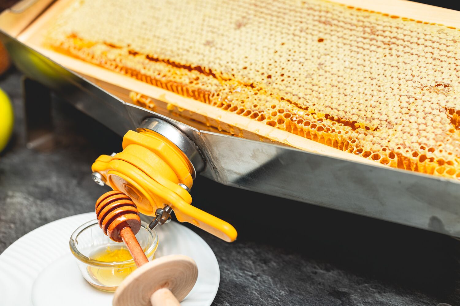 A honey extractor with honey dripping into a glass container.