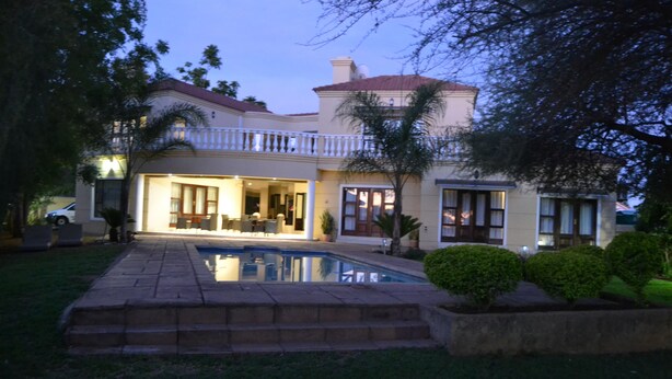 A two-story house with a swimming pool, a covered patio, and a well-maintained lawn. - The Capital Guesthouse (Gaborone)