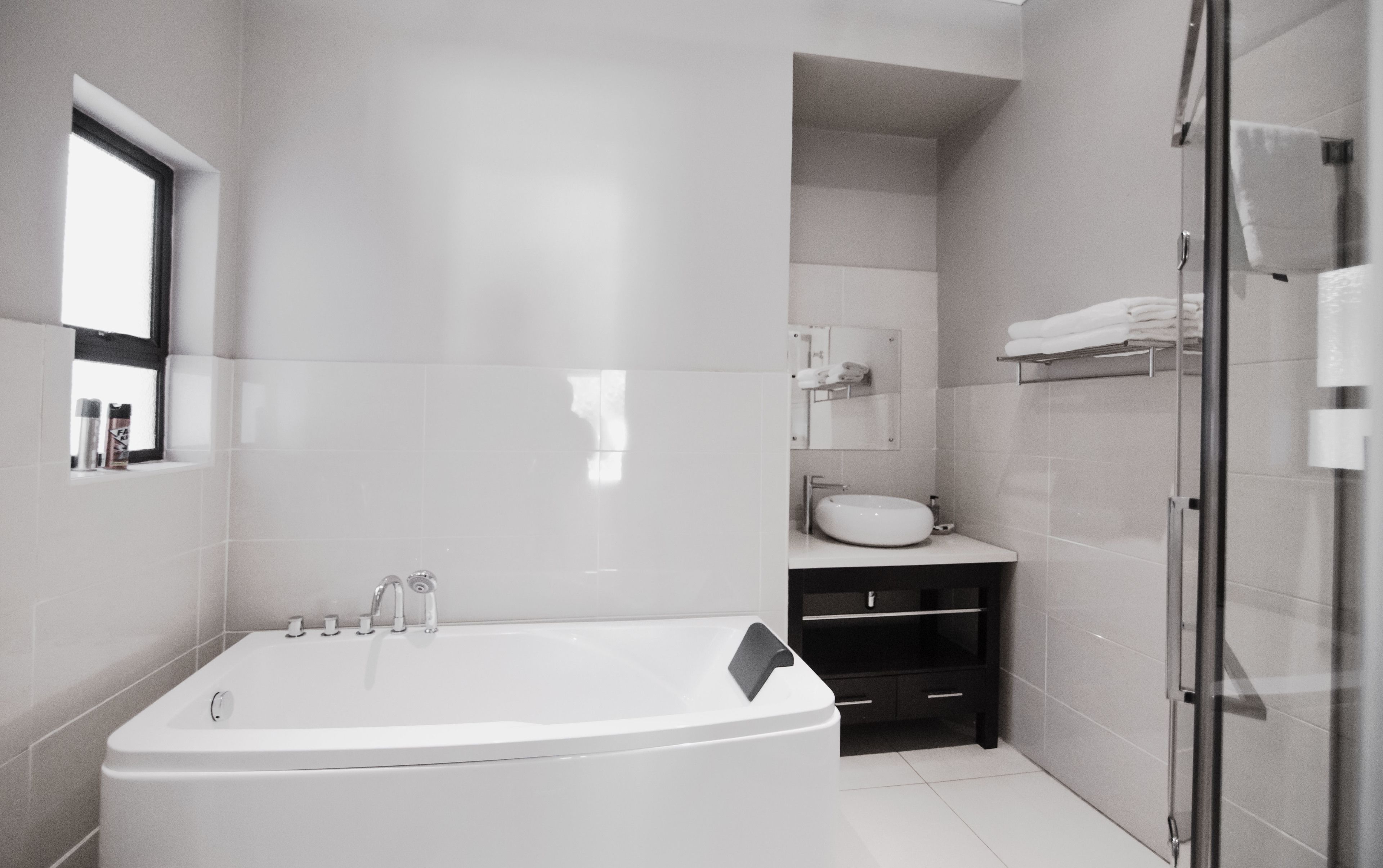 Un baño moderno con una bañera independiente, un box de ducha de vidrio y un lavabo con espejo.