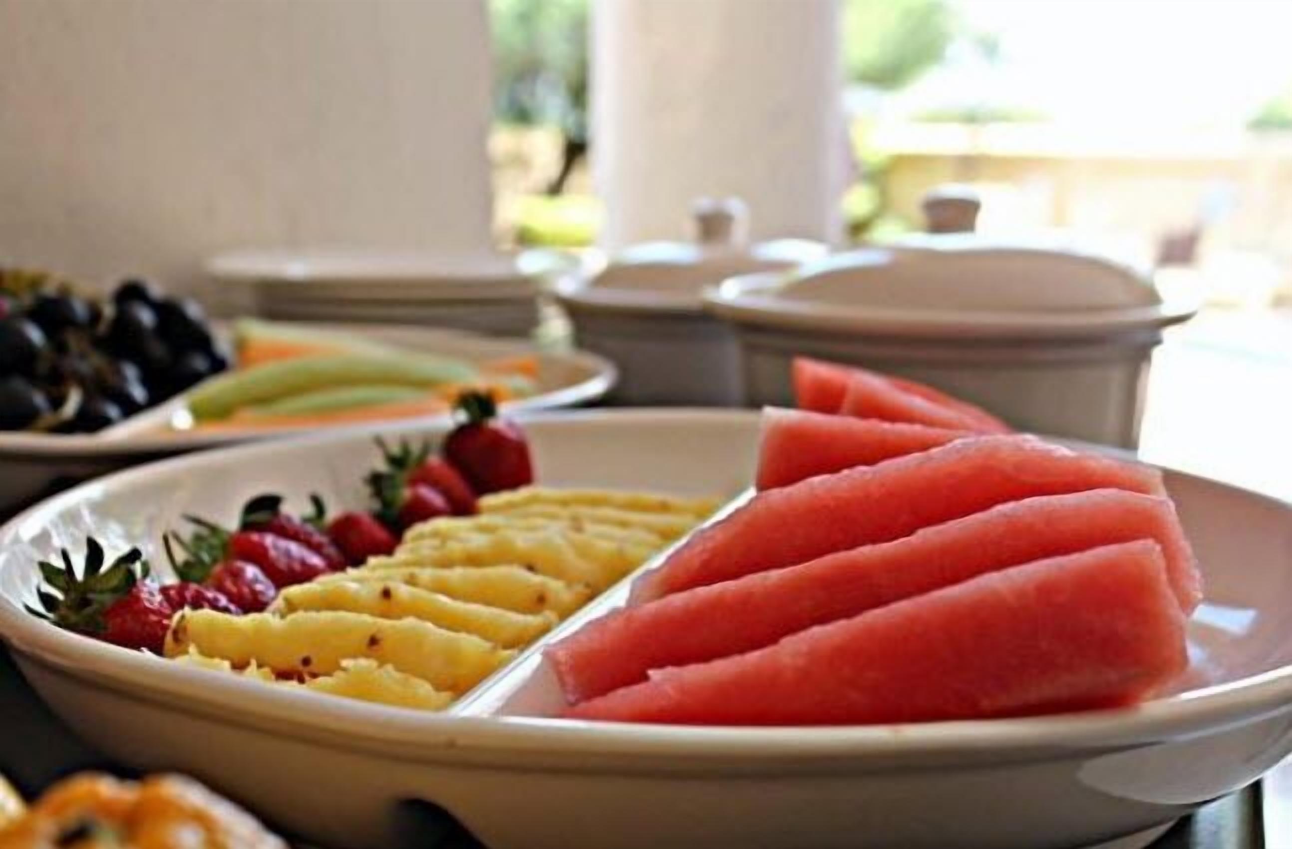 Un bufé con sandía, fresas y trozos de piña.