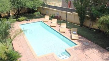 Relax by the pool surrounded by lush greenery and lounge chairs.
