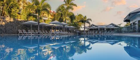 Alberca al aire libre, sombrillas en la alberca y camastros