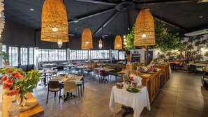 Un restaurant spacieux avec de hauts plafonds, de grands lustres en rotin suspendus et différents types de mobilier pour créer des espaces de détente variés.