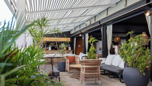 Un espace extérieur aménagé avec des meubles en osier, des plantes en pot et un patio couvert.