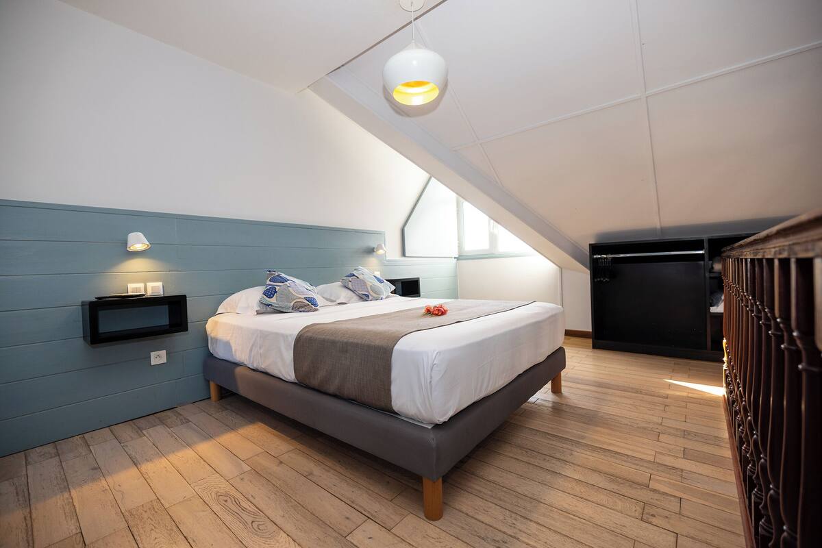Un dormitorio con cama, mesitas de noche, un armario y una ventana.