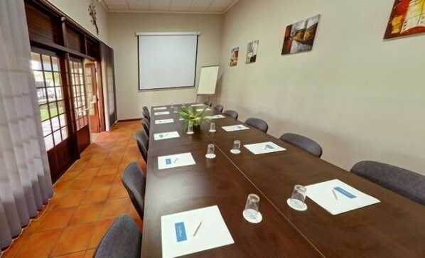 Una sala de conferencias con una larga mesa, sillas, una pantalla de proyector y obras de arte en las paredes.