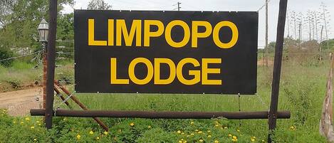 Ein Schild für 'Limpopo Lodge' mit schlichtem schwarzen Hintergrund und gelber Schrift.