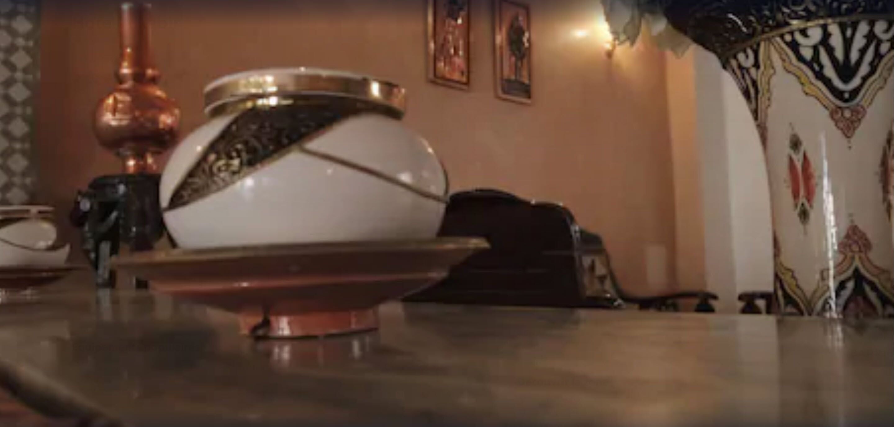 A table with a white bowl and a copper base.