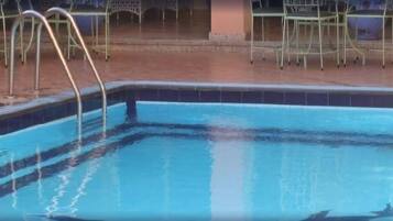 A swimming pool with metal railings and chairs around it.
