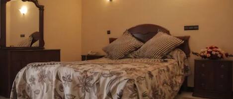 Un dormitorio con cama, cómoda, espejo y lámpara de pared.