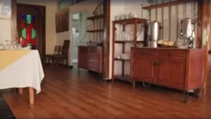 A room with a wooden floor, a table with a white tablecloth, and a bookshelf with various items. - Hotel Alkabir (Marrakech)