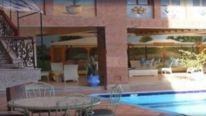 A pool area with a sun patio, outdoor seating, and a staircase leading to an upper level. - Hotel Alkabir (Marrakech)