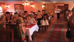 A restaurant with multiple tables and chairs, a red carpet, and a waiter walking through the space. - Hotel Alkabir (Marrakech)