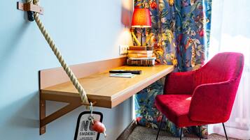 Ein Holztisch mit Seil, ein roter Stuhl, eine Lampe und Bücher.