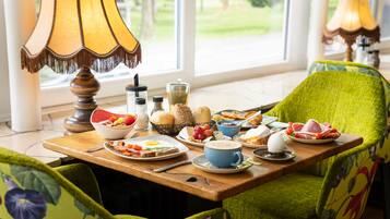 Una mesa de desayuno con diversos platos, una lámpara y sillas con tapicería floral.