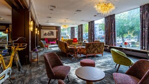 A hotel lobby with a large window, multiple seating areas, and a bicycle. - tinyTwice Hotel Bonn (Bonn)
