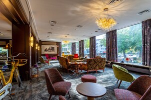 A hotel lobby with a large window, multiple seating areas, and a bicycle.