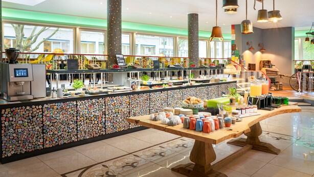 A breakfast buffet area with a variety of food items and a decorative wall. - tinyTwice Hotel Bonn (Bonn)