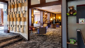 A lobby with a carpeted floor, a staircase, a seating area with chairs, a teddy bear on a shelf, and a framed sign. - tinyTwice Hotel Bonn (Bonn)