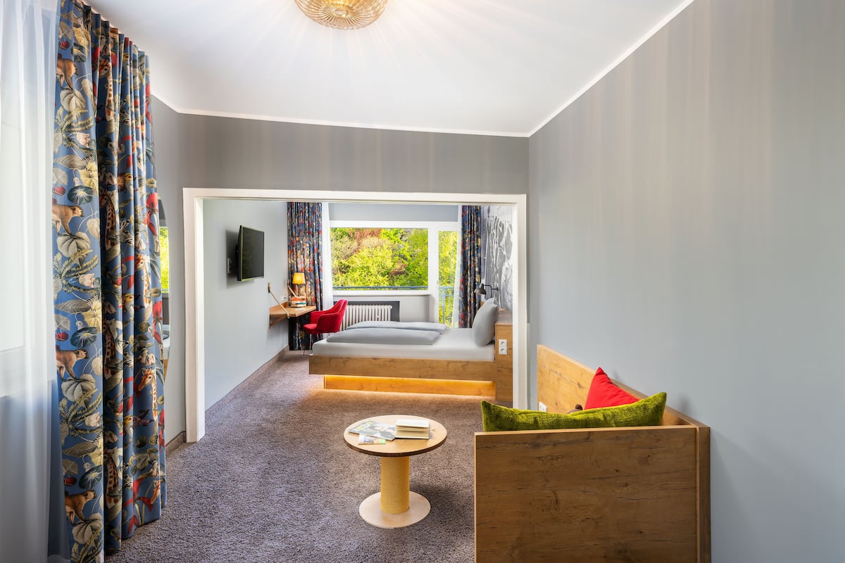 A modern room with a sofa bed, a small round table, and a wooden bench with cushions.